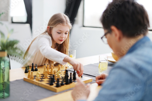 Serious little girl child competes in the park in chess with a parent.