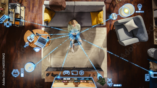 Φωτογραφία Top View Of Caucasian Woman In the Loft Apartment Sitting On Carpet Next To Couch and Connecting Smartphone to Smart Home System
