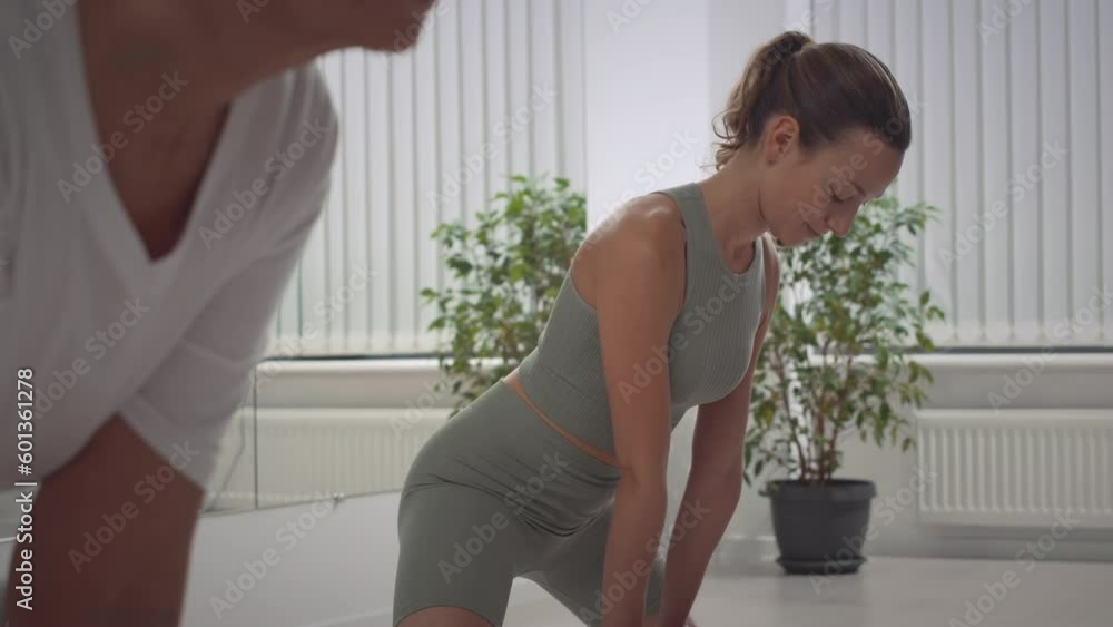 Tilt up of young flexible Caucasian woman in tight activewear using stretch blocks while stretching for splits during training in spacious studio Tilt up of young flexible Caucasian woman in tight activewear using stretch blocks while stretching for splits during training in spacious studio
