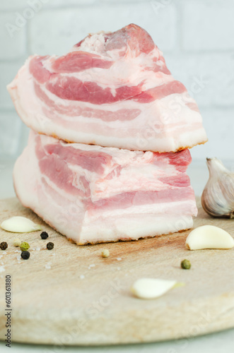 Fresh salted salo on a wooden board with garlic. Bacon. Concept Ukrainian traditional dish. Vertical orientation. Selective focus.