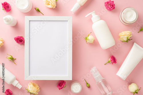 Natural skincare never looked so beautiful! This top view flat lay showcases elegant cream bottles, pump bottles, pipettes, and roses on a pastel pink background with an empty frame for messaging © ActionGP