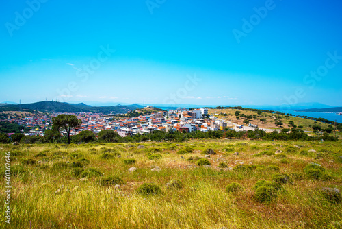A Turkish small town overlooking the sea and a green field on a summer and sunny day.
