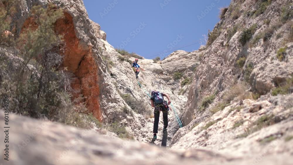 Via ferrata ascension by a couple sportsmen. View of mountain and mountaineers climbing in Alicante, Spain. Via ferrata ascension by a couple sportsmen. View of mountain and mountaineers climbing in Alicante, Spain.