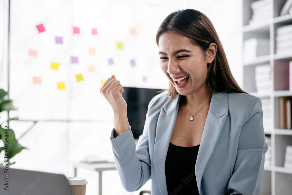 Accounting business concept, Accountant woman reads good news on laptop with excited and raising fist to celebrate achievement while working about investment with business planning finance Accounting business concept, Accountant woman reads good news on laptop with excited and raising fist to celebrate achievement while working about investment with business planning finance