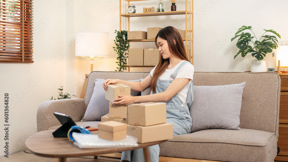 Young entrepreneur is packing products into cardboard boxes to p Young entrepreneur is packing products into cardboard boxes to p