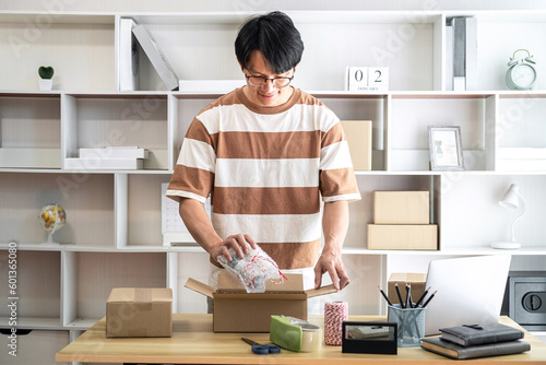 Male entrepreneur is packing the product into cardboard boxes fo