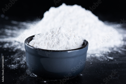 Tapioca starch in a bowl on a black background, dry cassava root.