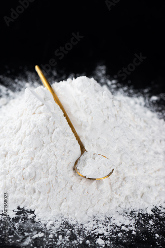 Bilde på lerret Heap of tapioca starch with spoon on a black background, dry cassava root