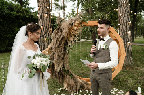 A handsome groom makes an oath to the bride at the wedding ceremony. wedding ceremony outside. nesta with the groom on the background of the wedding arch photo