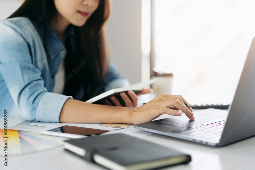 Woman architect holding notebook and typing data on laptop to sk Woman architect holding notebook and typing data on laptop to sk