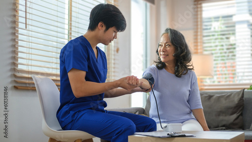 Male caregiver measuring blood pressure of a senior woman. Hypertension  medical and health care concept