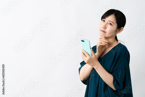 スマートフォンを持ちながら悩む若い女性 ライフスタイルイメージ