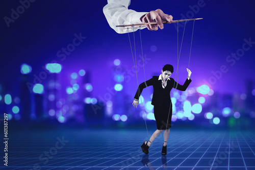Puppeteer holding businesswoman on strings © Creativa Images