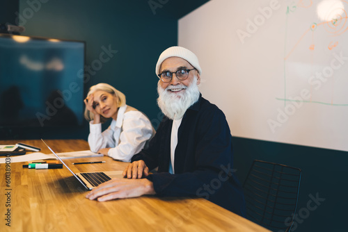 Happy mature man using laptop and woman looking at camera