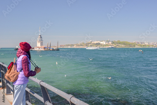 A woman tourist enjoys a view of the Maidens Tower. The Maidens Tower, also known as Leanders Tower from the medieval Byzantine period, is a tower 