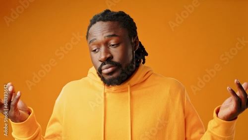 Clueless african man shrugging shoulders against yellow background photo