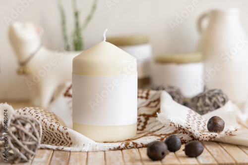 Candle with blank label on a wooden table Close up, copy space, boho ethnic mock up