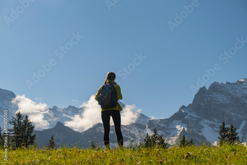 Sporty woman standing in front of snow mountains and enjoying view of Switzerland nature. Wanderlust, sport, beauty in nature.
