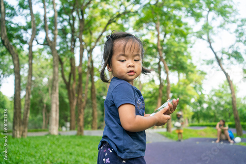 Portrait of happy asian toddler girl walking in city public tree park