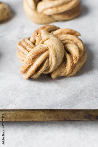 Swedish cinnamon buns dough on a parchment lined baking pan, unbaked cinnamon twists, process of making Kanelbullar photo