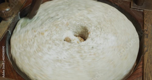 The baker grinds grain into flour. Antique hand mill in operation with an authentic 200 year old millstone