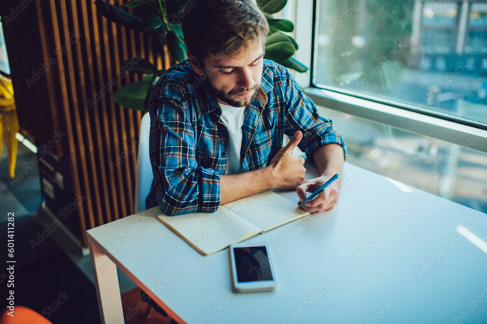 Focused man taking notes on planner at table Focused man taking notes on planner at table