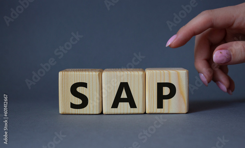 SAP - Systems Applications Products. Wooden cubes with word SAP . Businessman hand. Beautiful grey background. Business and System Application Product concept. Copy space.