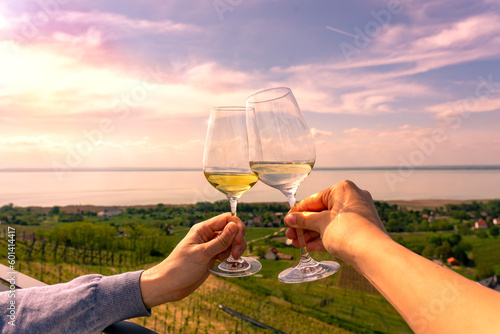 romantic celebratory toast with wine glasses in a Vineyard wine garden at Lake Balaton in Baracsony Hungray with beautiful view sunset