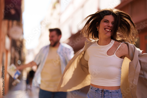Playful couple having fun while running on the street.