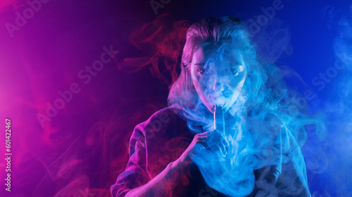 Woman smokes vape. Girl releases steam from device for vaping. Lady vaper. Woman with electronic cigarettes. Vaper on neon background. Vape pen for smoking vapor. Hobby vaping. Vape smoker
