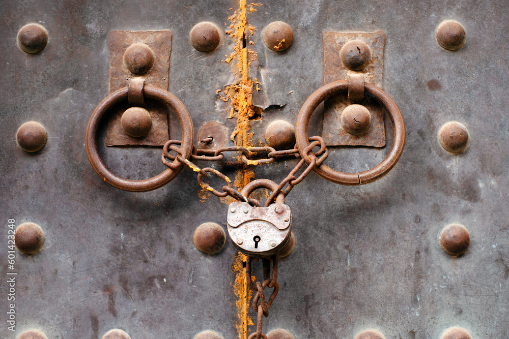 Old metal rusty medieval door locked with a chain and padlock Old metal rusty medieval door locked with a chain and padlock