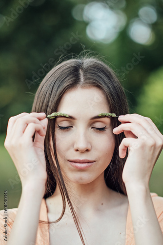 Natural Eyebrows cosmetics, eyebrow makeup and care trends. Candid portrait of young woman holding green plants herbs near eyelashes
