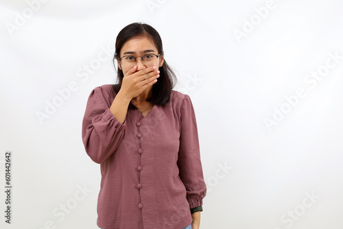 Funny expression of young asian woman standing while covering her mouth. Isolated on white