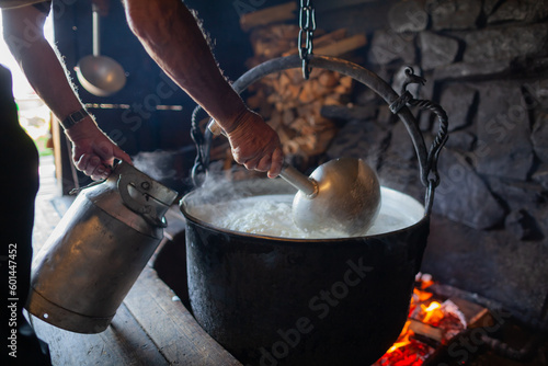 Bacówka w Jaworkach i okolice. Osoba nabierająca ugotowane mleko z garnka na ognisku. 