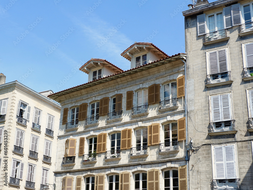 French vintage facades of faded beige and white colours with elegant shuttered windows on the streets seen from outside in Bayonne, Basque country, France