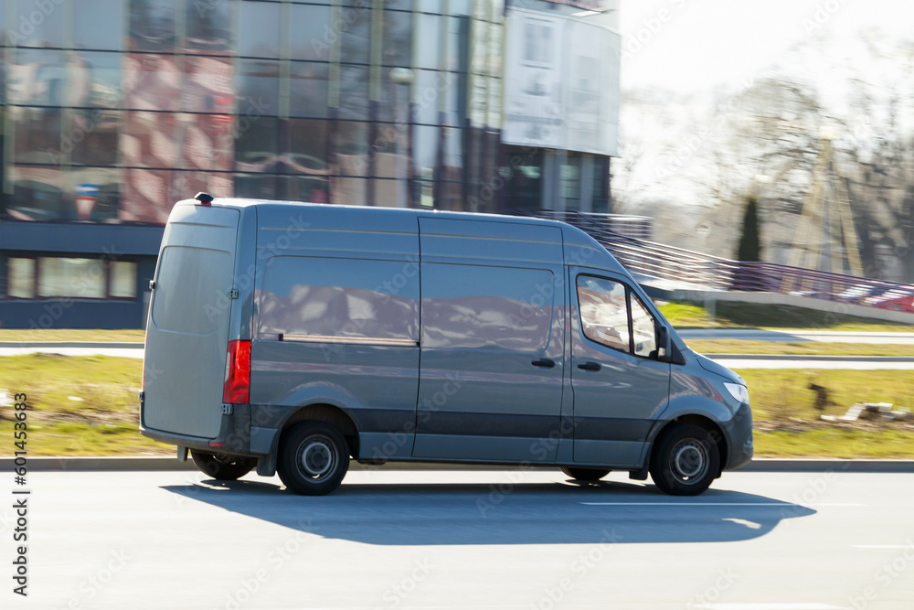 A gray van drives down the street. A moving cargo minibus. Cargo transportation, commercial transport. Motion blur