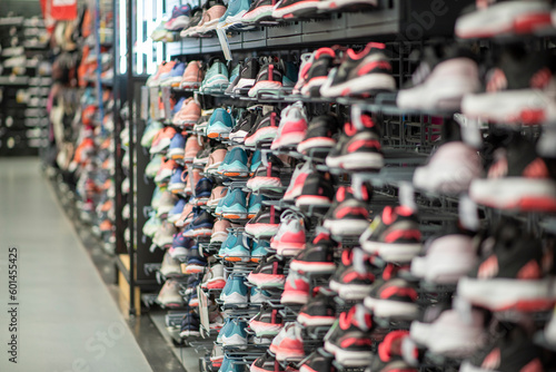 Shop display of a lot of Sports shoes on a wall. A view of a wall of shoes inside the store. Modern new stylish sneakers running shoes for men and women - Dubai UAE December 2019. High quality photo