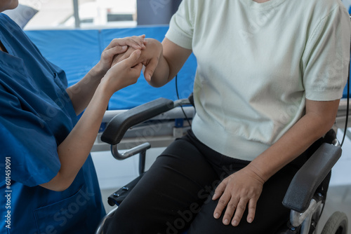 Asian senior care nurses and grandmothers provide caring support to elderly women hand clasp to encourage exercising with elder disabled person patient with caregiver in nursing care. © makibestphoto