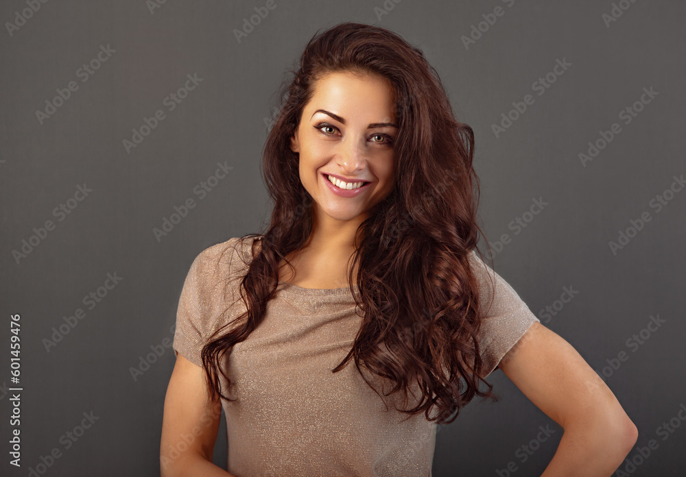 Fototapeta premium Beautiful makeup toothy enjoying smiling woman with long brown healthy curly hair style in fashion shirt clothing. Closeup studio portrait on grey