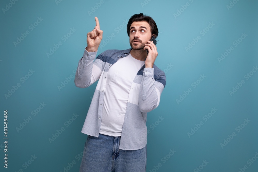 nice brunette guy in casual style shows with his hand for having an idea on a studio background nice brunette guy in casual style shows with his hand for having an idea on a studio background