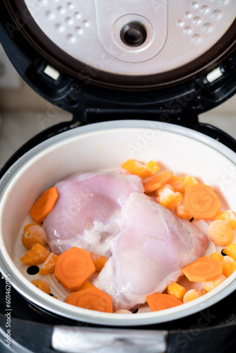 chicken meat and carrot pieces in a double boiler, top view. Steamed meat and vegetables
