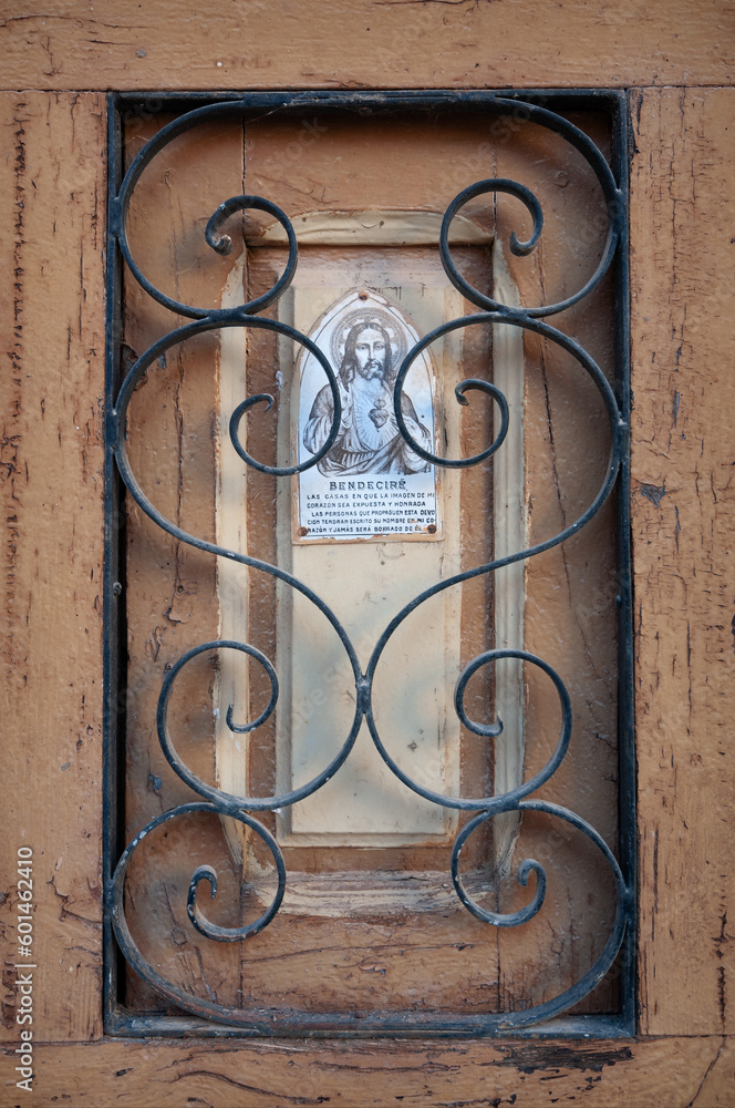 Una placa del corazón de Jesús en una ventana con reja de hierro en un pueblo español.
