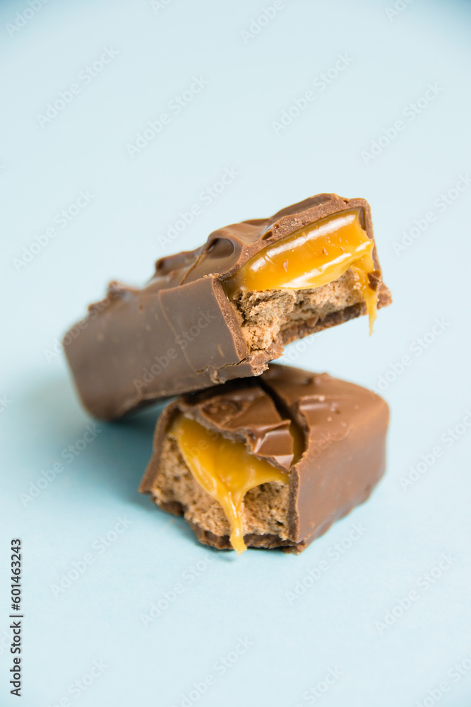 Appetizing pieces of a chocolate bar with caramel macro on a blue background Appetizing pieces of a chocolate bar with caramel macro on a blue background