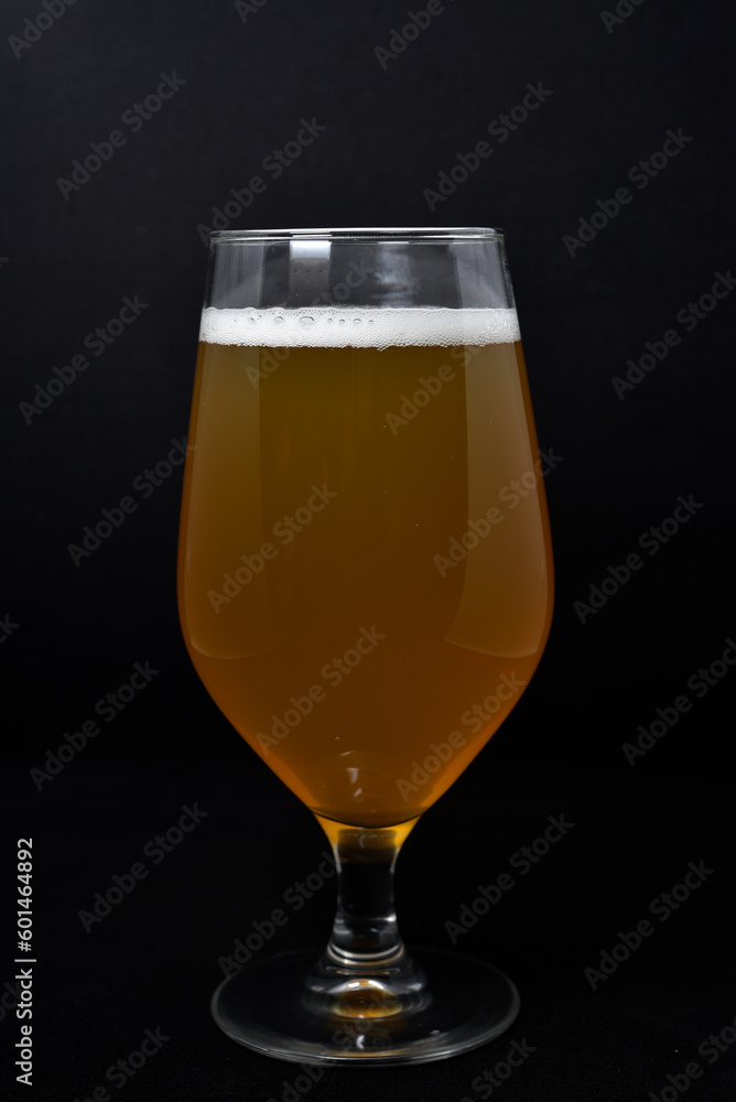 A glass of light beer on a black background. Fresh beer from a glass. A glass of light beer on a black background. Fresh beer from a glass.