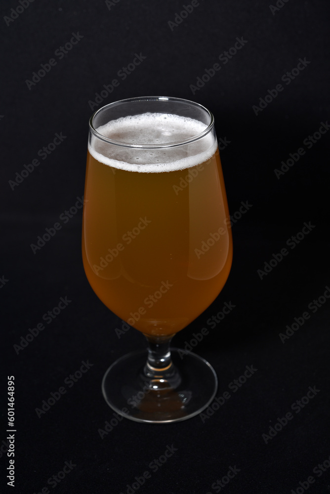 A glass of light beer on a black background. Fresh beer from a glass.