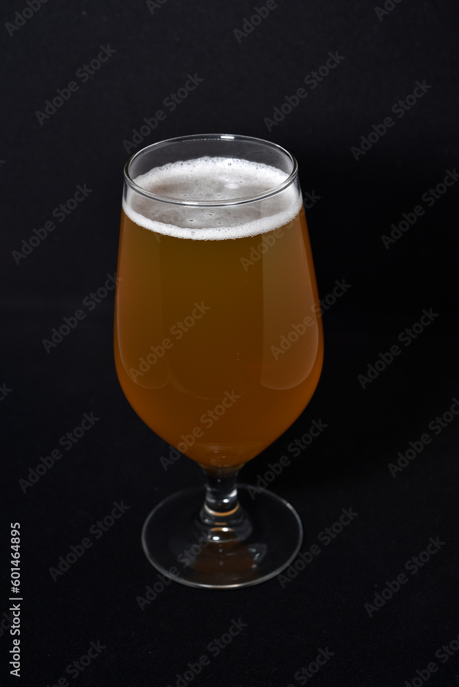 A glass of light beer on a black background. Fresh beer from a glass. A glass of light beer on a black background. Fresh beer from a glass.