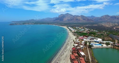 Rising Flight Above Lagoon and Palm Tree Resort with Boat Near the Beach and Mountains in Background