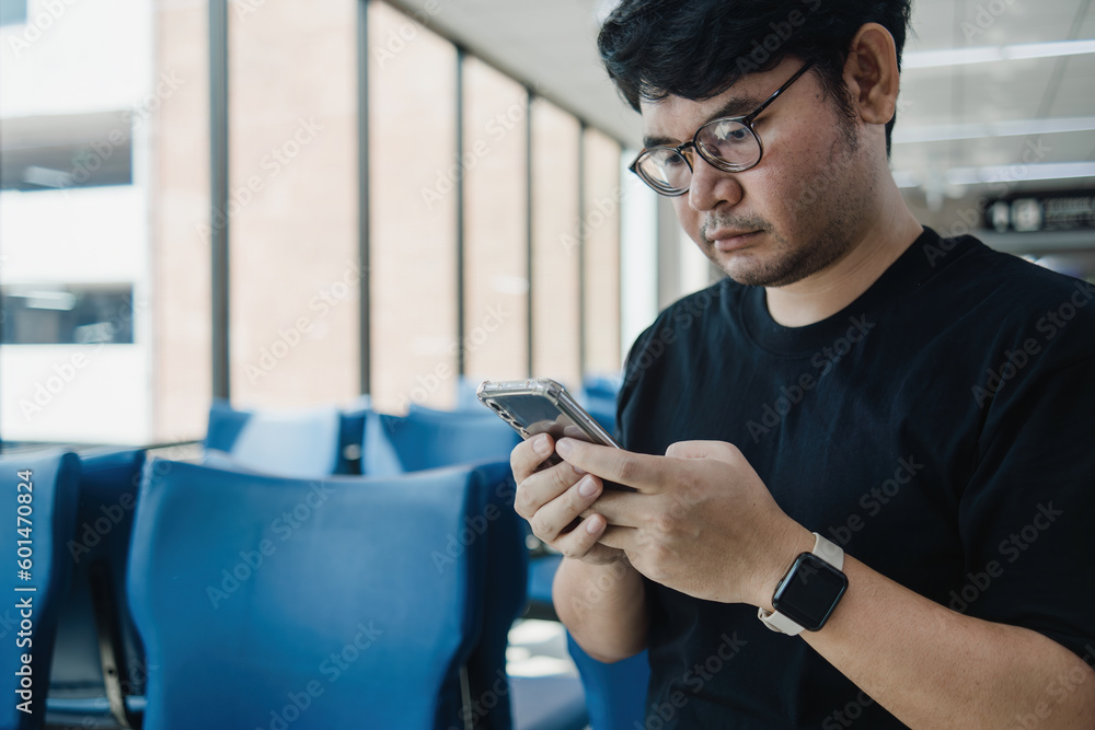 chatbot gpt concept, asian man sitting down while looking at his smartphone chatbot gpt concept, asian man sitting down while looking at his smartphone