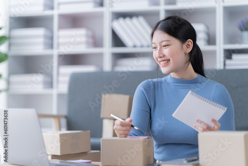 Startup SME small business entrepreneur of freelance Asian woman using a laptop with box Cheerful success Asian woman her hand lifts up online marketing packaging box and delivery SME 