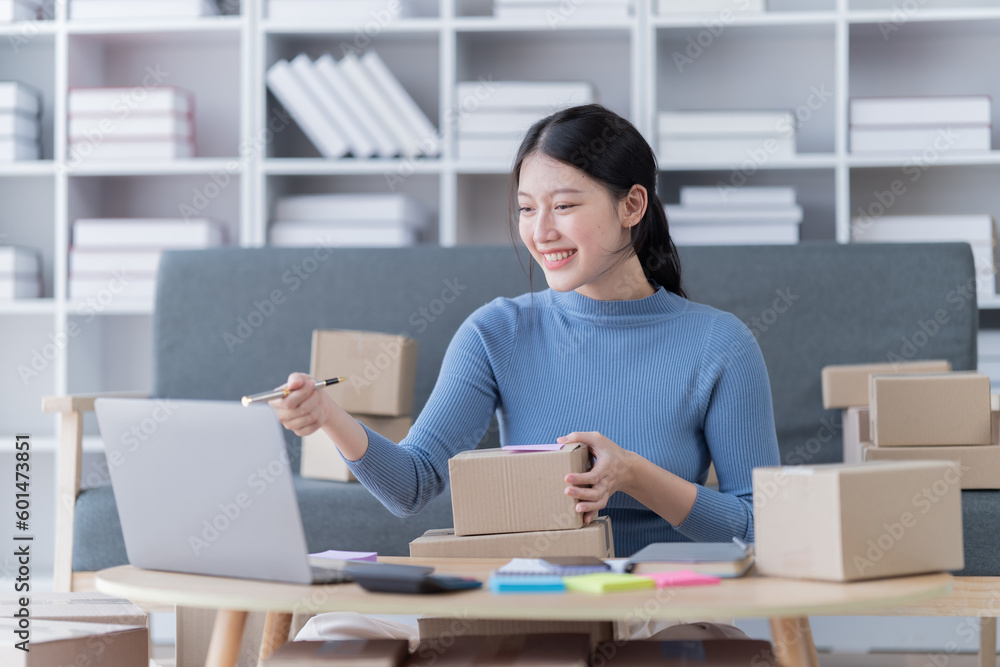 © Tj - Asian business woman siting on sofa using a laptop and notebook checking order online shipping boxes at home. Starting SME Small business entrepreneur freelance. Online business, SME Work © Tj - Asian business woman siting on sofa using a laptop and notebook checking order online shipping boxes at home. Starting SME Small business entrepreneur freelance. Online business, SME Work